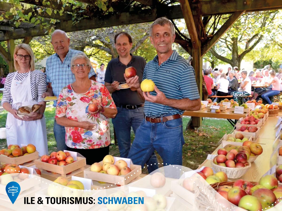 Fünf Personen stehen hinter einem Stand mit verschiedenen Apfelsorten