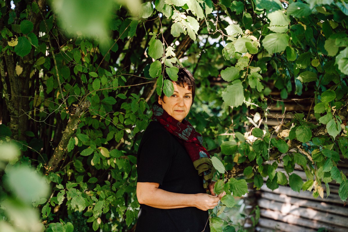 Ulrike Gschwendtner steht inmitten eines Haselnussstrauchs