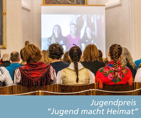 Drei junge Frauen in Tracht hören sich einen Vortrag an.