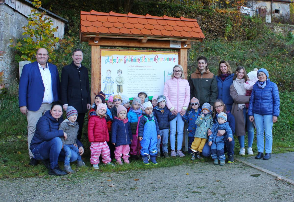 Aufseßer Kita-Kinder und Verantwortliche stehen vor der Infotafel am Erlebnisgässla