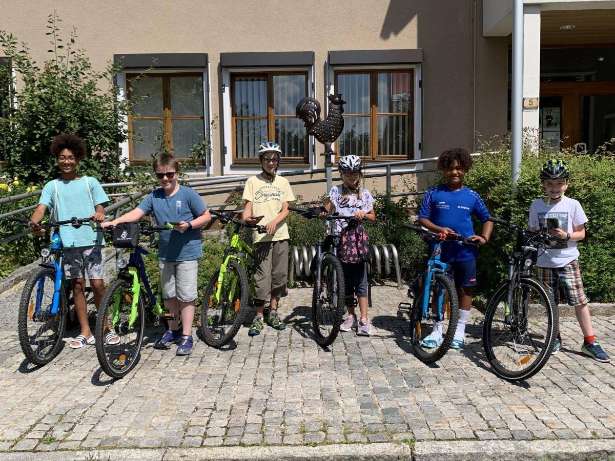 Fahrrad und Handy parat – die Actionbound-Tester starten das Hahnbacher Abenteuer bei der Jubiläumsfahne vor dem Rathaus.