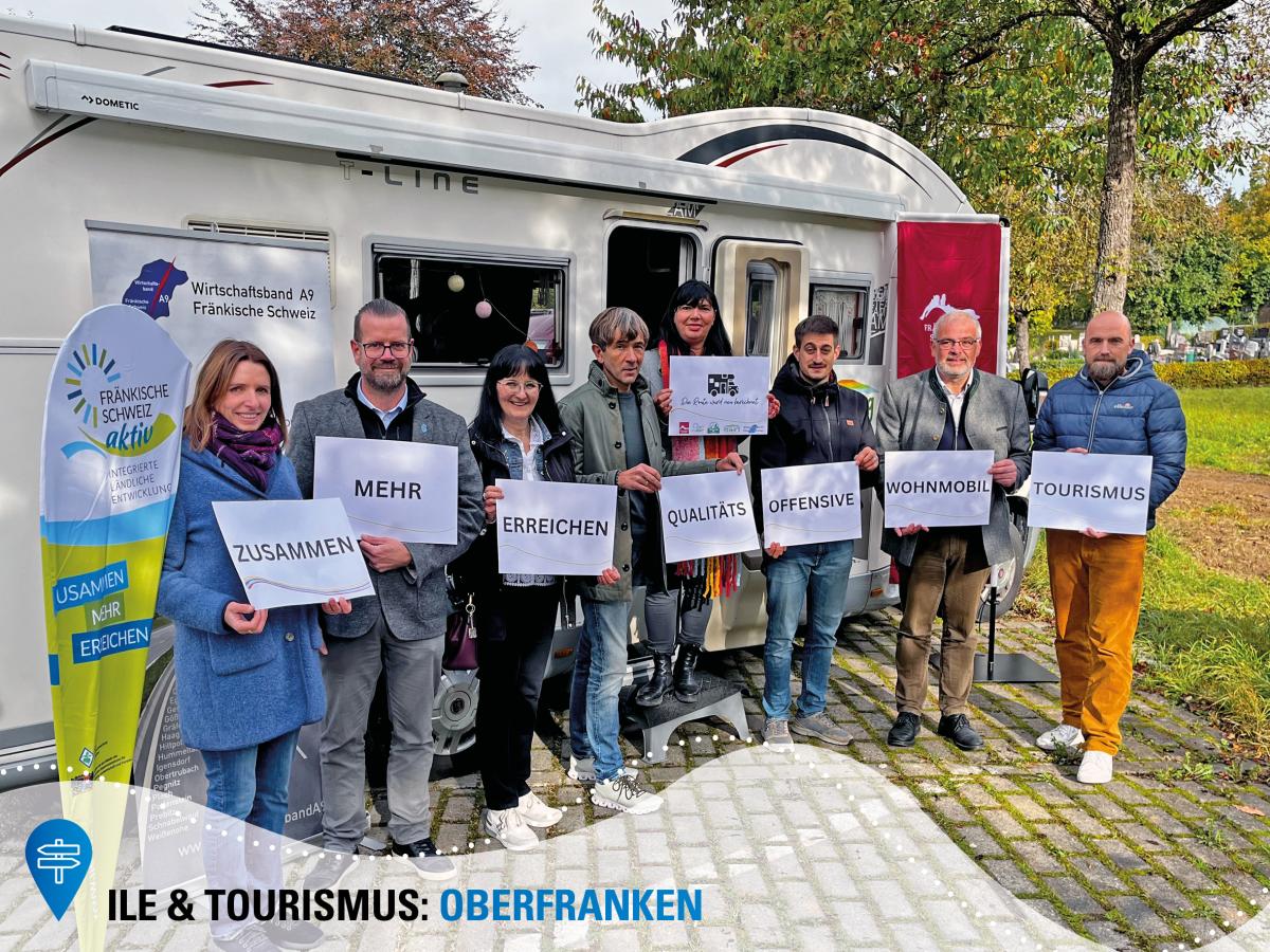 Mehrere Personen stehen mit Schildern in der Hand vor einem Wohnmobil.