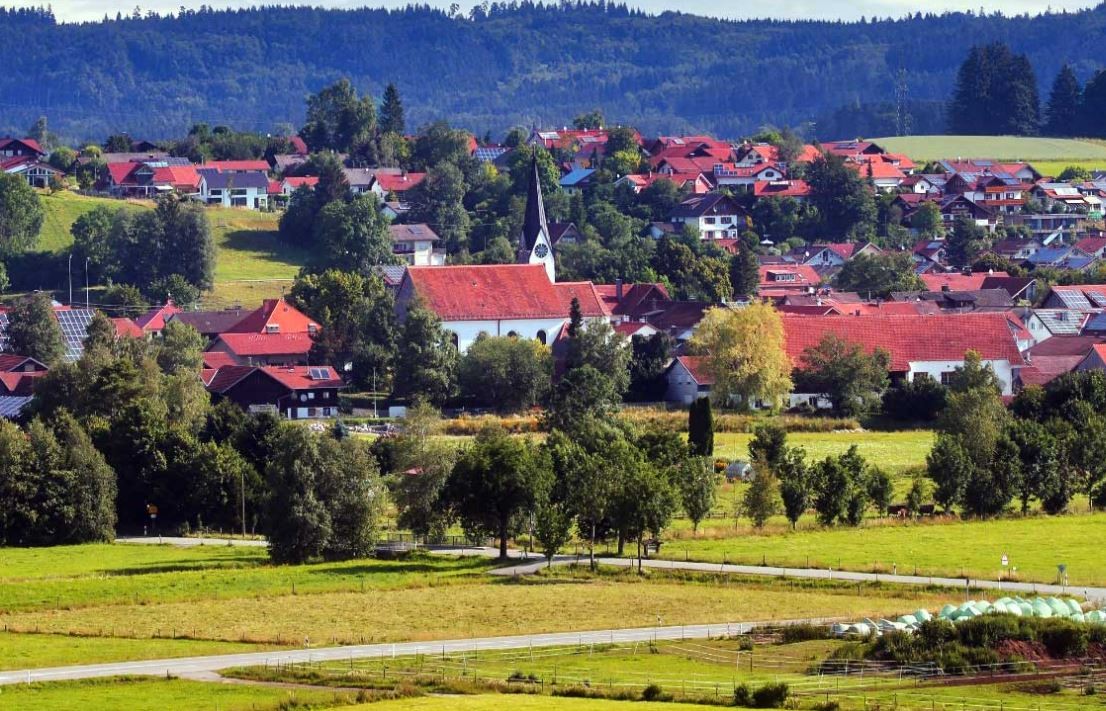 Ansicht der Gemeinde Aitrang mit Kirche, Häusern und Bäumen